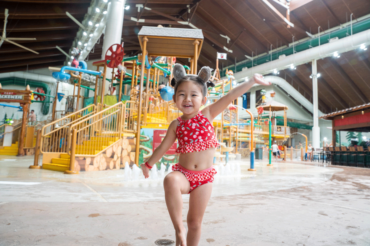 Little girl in swimsuit posing inside Great Wolf Lodge in LaGrange, Georgia, with the waterpark in the background.