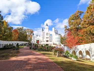 A white castle is surrounded by colorful fall foliage in the mountains
