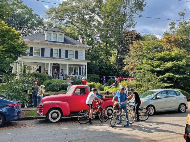 A band playing on the front porch of a home in Decatur with people in the yard and on bikes listening to the music