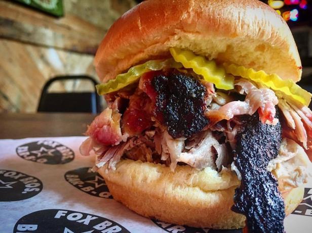 A giant barbecue sandwich with toppings spilling over the side