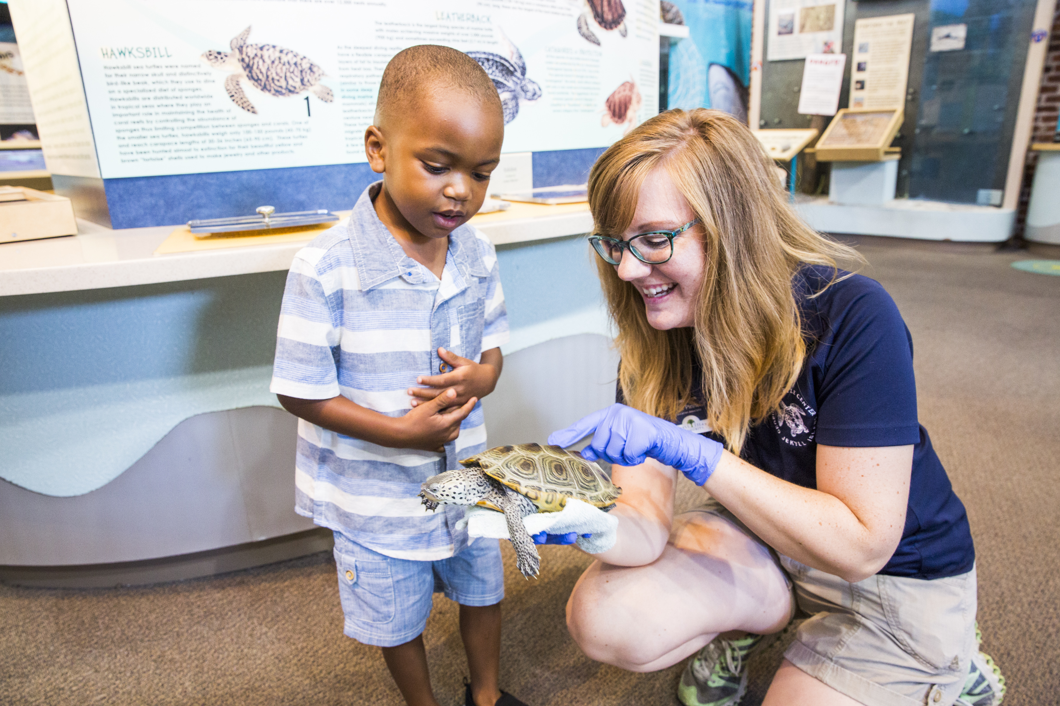 A young woman and a small boy look at a turtle shell