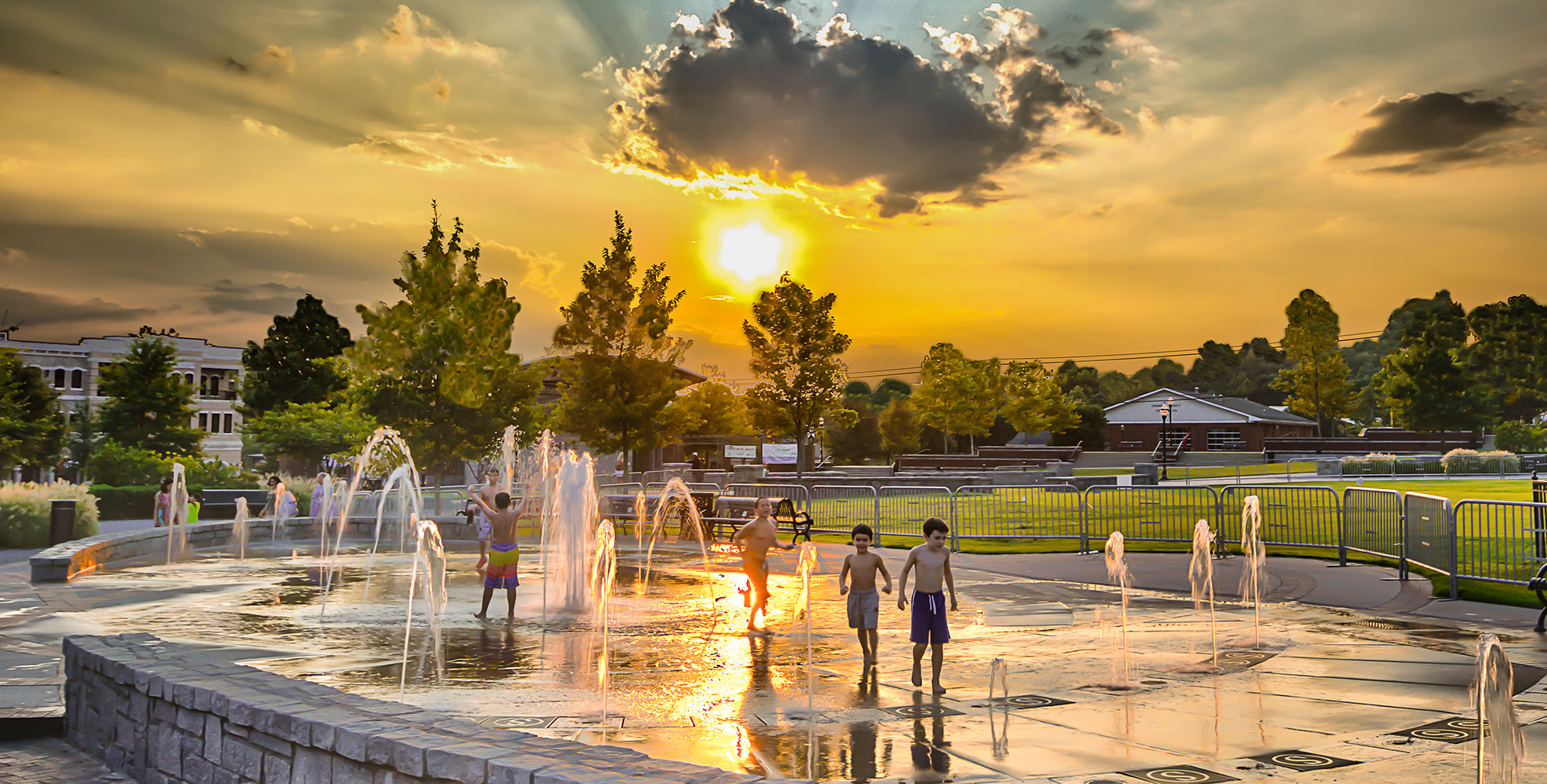 Children playing in fountain in downtown Suwanee, Georgia at sunset.