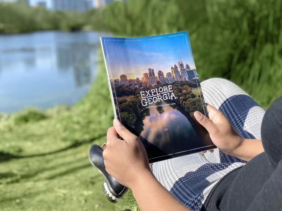 Person holding a 2022 Explore Georgia Travel Guide in Piedmont Park in Atlanta, Georgia