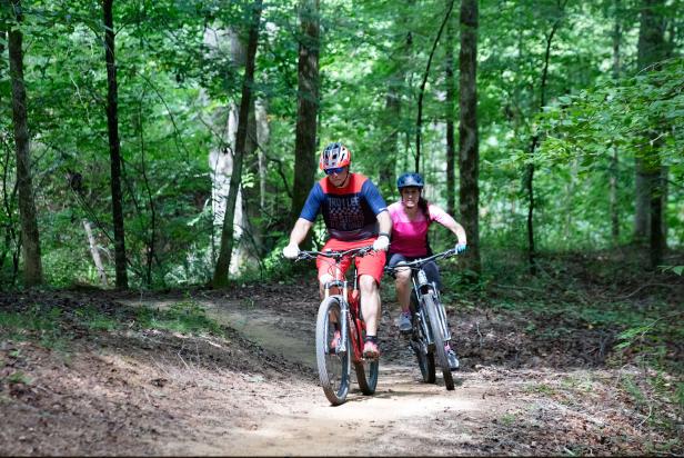 Man and Woman bike on wooded path