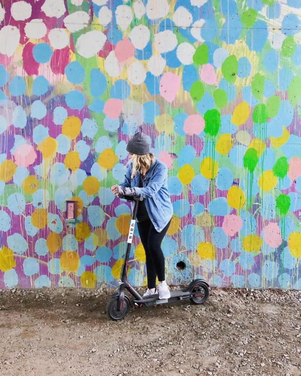 Woman on a scooter in front of a mural on the Atlanta BeltLine. Photo by @miss.justine.olivia