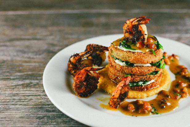 Fried green tomatoes with shrimp and grits on a white plate