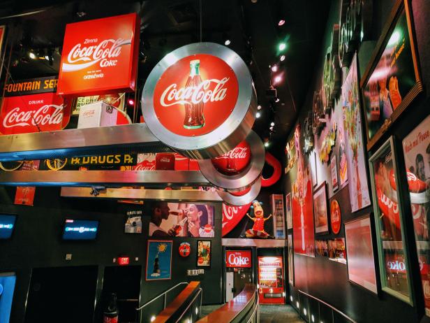 Multiple red and white Coca-Cola signs hanging inside the World of Coca-Cola in Atlanta, Georgia. Photo by @discoveratlanta.
