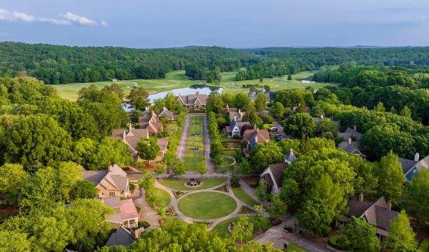 Bird's eye view of Barnsley Resort's cottages, courtyard and golf course with rolling hills of trees in the distance