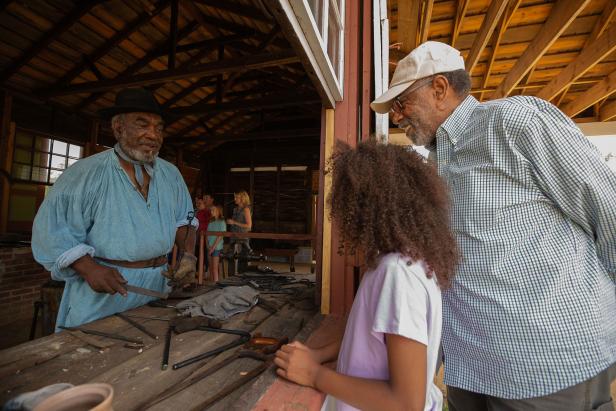 Blacksmith demonstrates his work to a family at Historic Westville in Columbus, Georgia